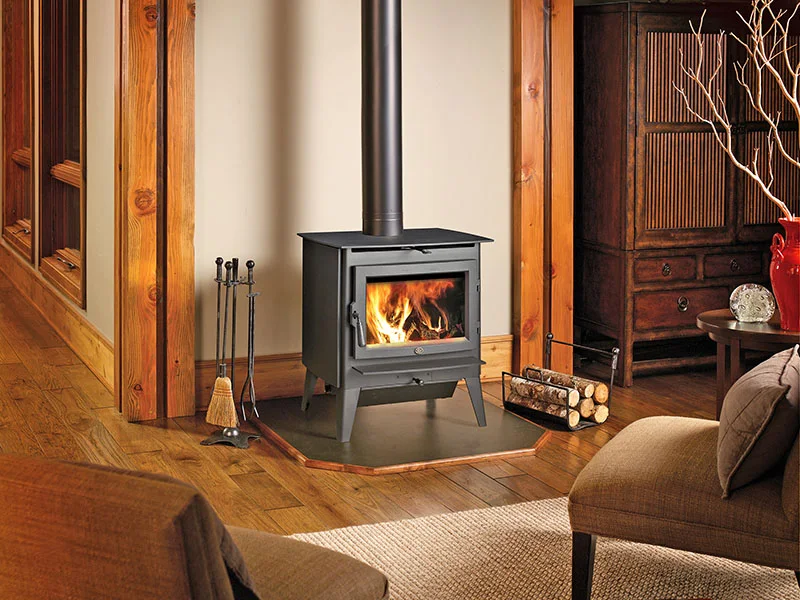 Lopi Evergreen wood stove installed on a hearth pad in a timber-frame living room