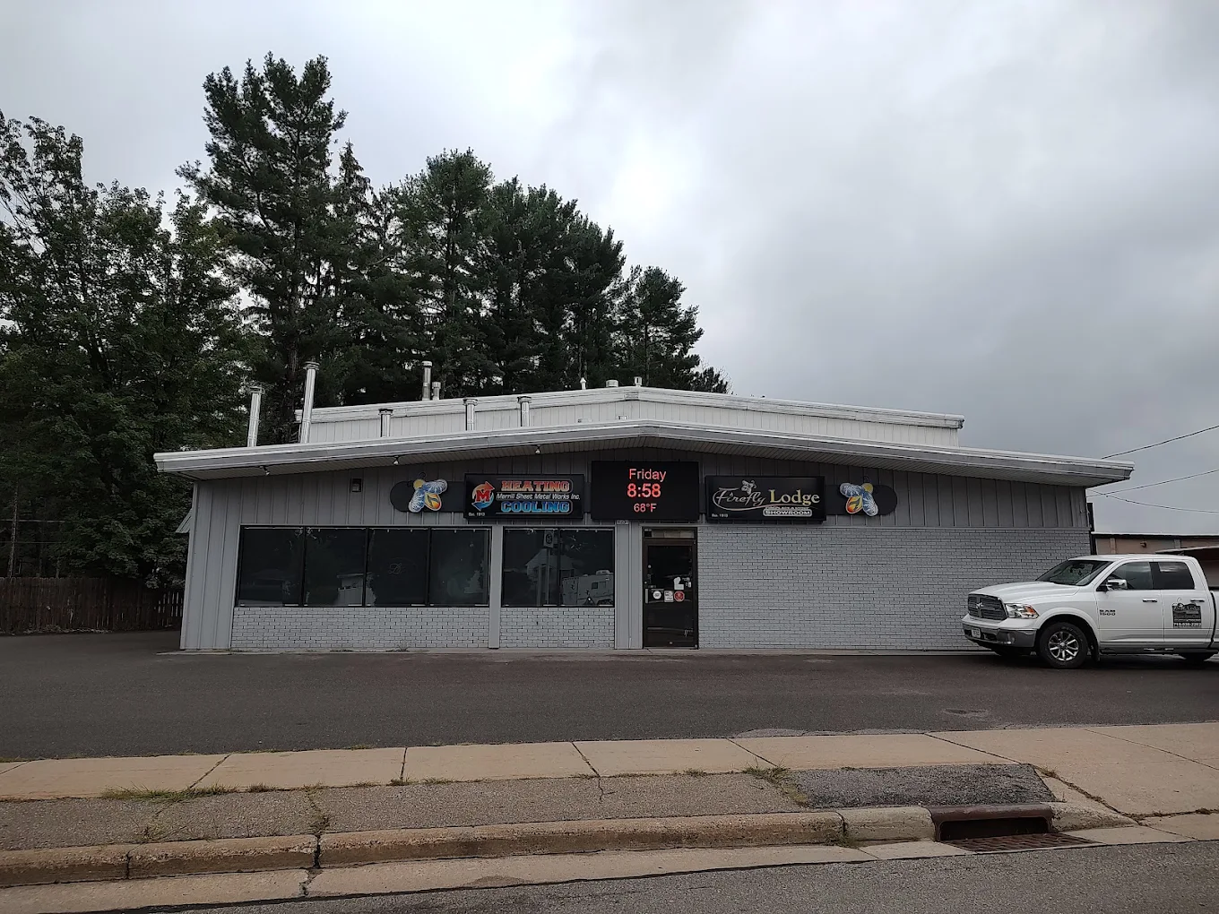 1204 N Center Ave in Merrill — one building carrying both signs, Merrill Sheet Metal Works and the Firefly Lodge showroom