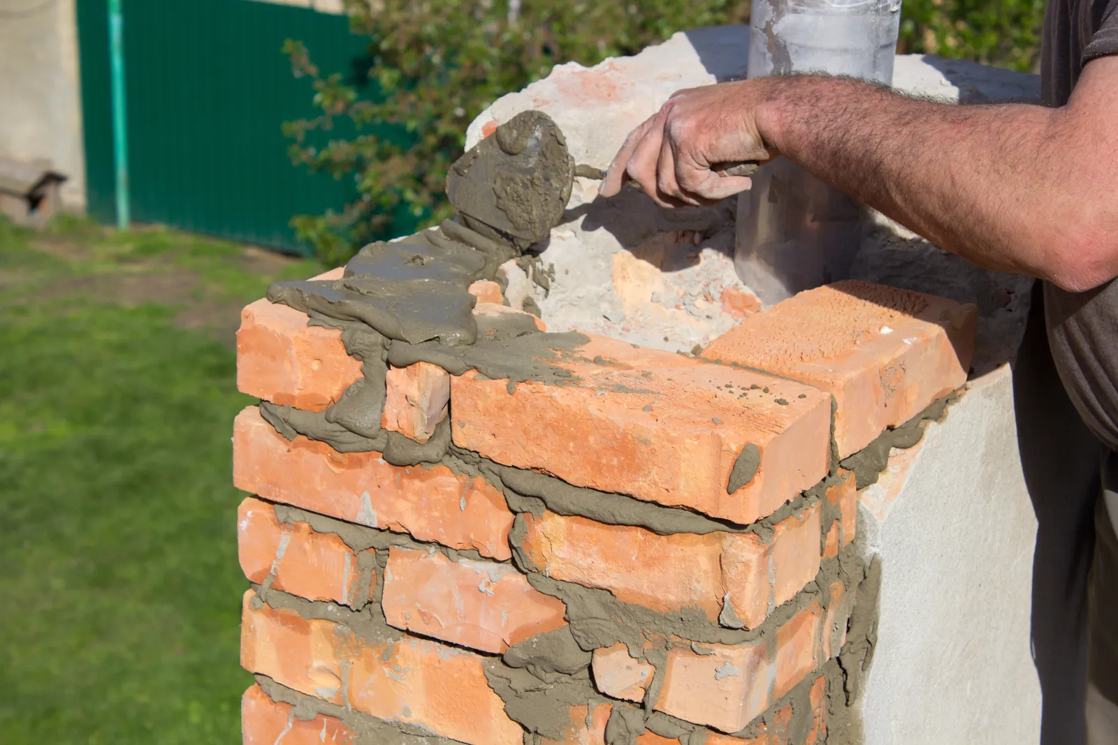 Fresh mortar going down on a brick chimney mid-rebuild